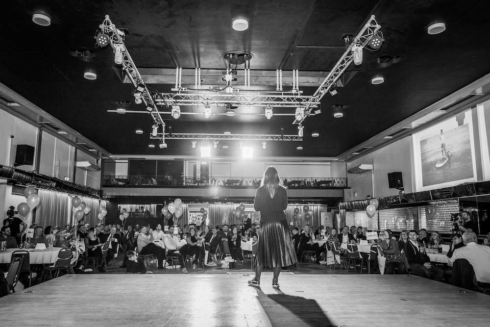 A black and white photo of a businesswoman standing on a stage.