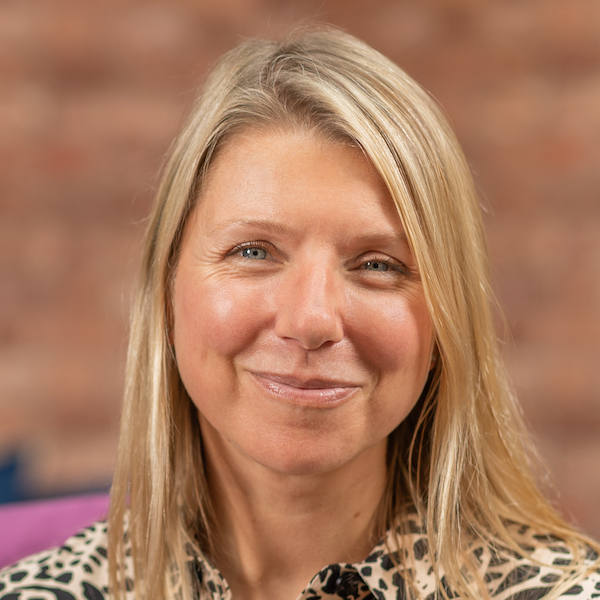 A woman in a leopard print shirt is smiling.