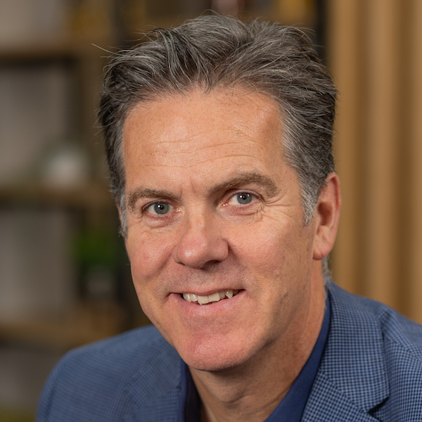 A man in a blue suit smiles for the camera.