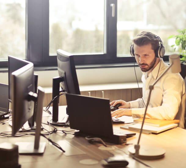 A man sitting at a desk engaged in innovation, working on an ICT project with his computer.